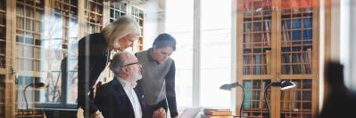 Three people conferring over documents